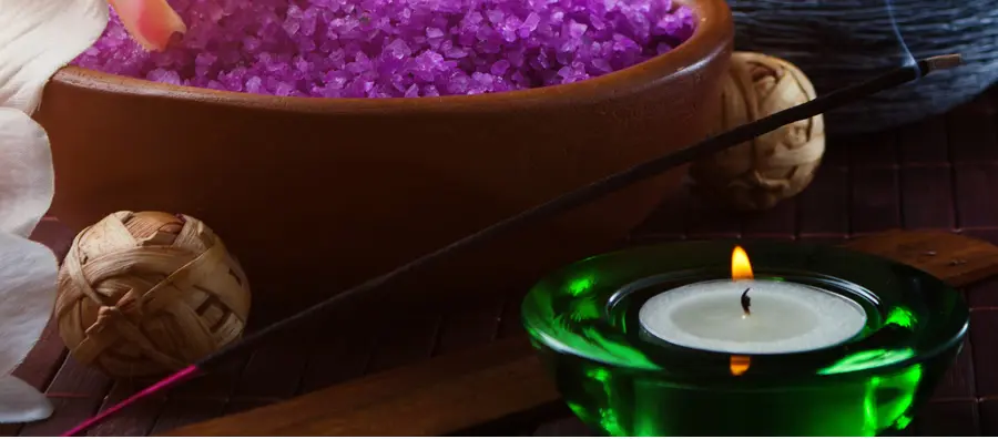 A bowl of purple rice next to a candle.